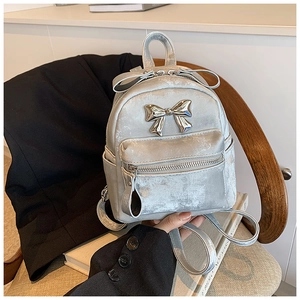 Détail d'un mini sac à dos argenté avec nœud métallique et texture en similicuir lisse