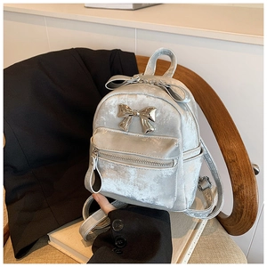 Vue détaillée du mini sac à dos argenté métallisé avec grand nœud décoratif et fermetures