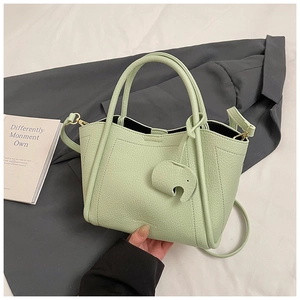 Detail of mint green bucket bag with lychee texture and elephant charm accessory