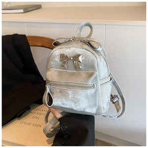 Mini sac à dos argenté avec nœud métallique sur chaise en bois avec accessoires lifestyle