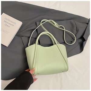 Detail of light green litchi texture bucket bag with curved top and golden bottom studs