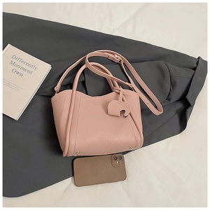 Close-up of pink litchi grain bucket bag with cute elephant charm and metal studs