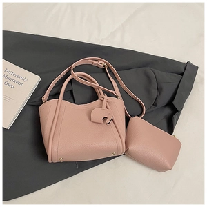Detail of pink lychee leather bucket bag with logo and elephant charm accessory