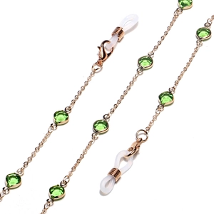 Detailed close-up of golden eyewear chain featuring green faceted beads and lobster clasps