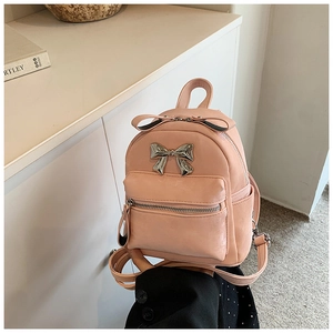 Gros plan détaillé d'un mini sac à dos rose avec des nœuds décoratifs et du métal