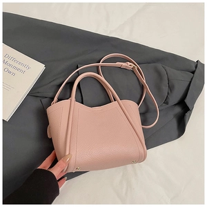 Detail of pink lychee leather bucket bag with top handles and metal protective feet
