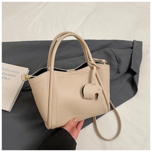 Close-up of beige lychee grain leather bucket bag with cute elephant charm and logo