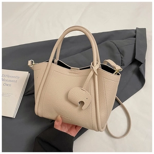 Detailed macro of beige lychee grain leather tote featuring a cute elephant charm