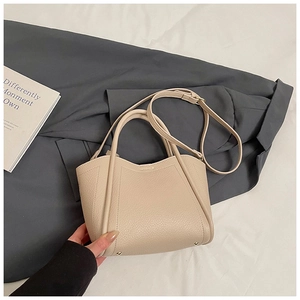 Detail of beige lychee grain leather bucket bag with wavy edge and golden metal studs
