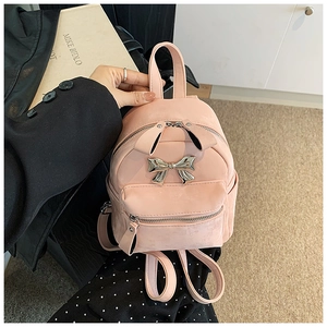Vue détaillée d'un mini sac à dos rose en similicuir avec un nœud en métal argenté