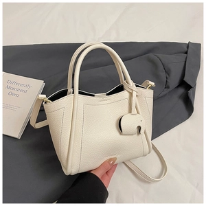 Detail of cream white lychee leather bucket bag with cute elephant charm and thin strap