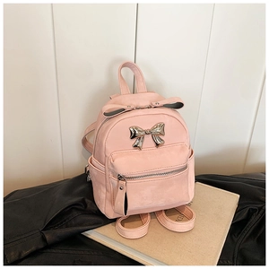 Vue détaillée d'un mini sac à dos rose avec noeud métallique sur veste en cuir