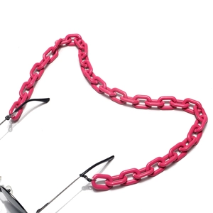 Détail d'une grosse chaîne de lunettes en acrylique magenta sur monture noire