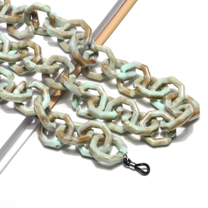 Close-up of mint green and amber acrylic glasses chain with hexagonal link pattern