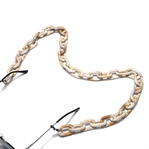 Détail de chaîne à lunettes en acrylique marbré ambre avec attaches en caoutchouc noir