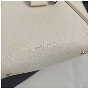 Macro detail of lychee grain leather handbag base with gold feet and brand logo