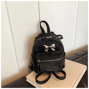 Vue détaillée d'un mini sac à dos noir avec boucle nœud dorée et texture vintage