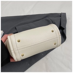 Detail of white lychee grain leather bucket bag base with four protective gold metal feet