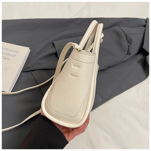 Detail of white lychee leather texture and clean stitching on a minimalist bucket bag