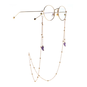 Fashion gold round glasses with beaded metal chain and purple wing charms on white background