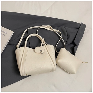 Close-up of beige lychee grain bucket bag with a small coin purse and elephant charm