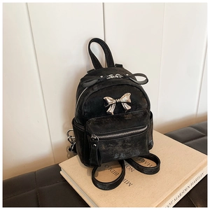 Détail du mini sac à dos noir avec nœud en métal argenté et texture de cuir rétro