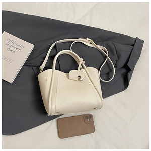 Detail of cream white leather bucket bag with cute elephant charm and thin shoulder strap