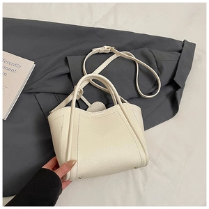 Detailed macro shot of creamy white lychee grain leather bucket bag with metal feet