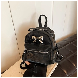 Détail d'un mini sac à dos noir avec texture vintage et décoration de nœud en métal doré
