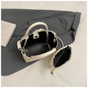 Close-up of cream white bucket bag with pebble leather texture and magnetic snap closure