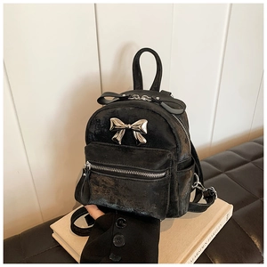 Détail du mini sac à dos noir avec texture cuir vintage et nœud décoratif argenté