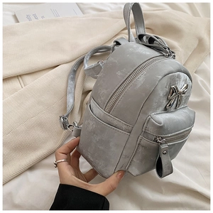 Gros plan détaillé d'un mini sac à dos gris métallisé avec un nœud décoratif argenté