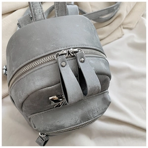 Détail d'un mini sac à dos gris avec nœud en métal argenté et similicuir texturé élégant