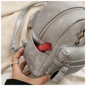 Vue détaillée du mini sac à dos gris métal avec rouge à lèvres dans la poche latérale