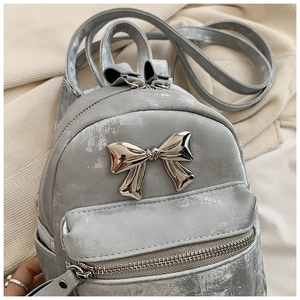Vue détaillée du petit sac à dos gris nacré avec un nœud métallique décoratif
