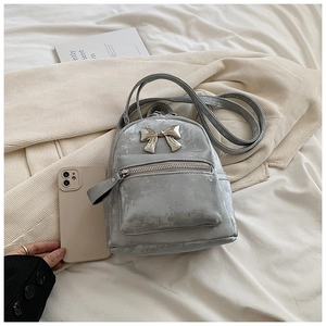 Détail d'un mini sac à dos gris en velours avec nœud métallique et poche avant zippée