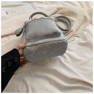 Détail du mini sac à dos gris argenté avec finition métallique et poche zippée