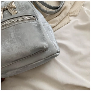 Détail du nœud argenté et de la texture velours d'un mini sac à dos élégant