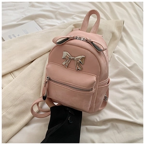 Vue détaillée d'un mini sac à dos rose avec nœud métallique argenté et texture fine