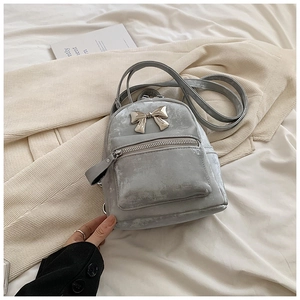 Détail d'un mini sac à dos en velours gris avec nœud en métal doré et poche zippée