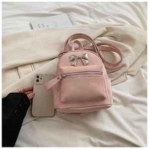 Détail d'un mini sac à dos en similicuir rose avec nœud métallique et poche zippée