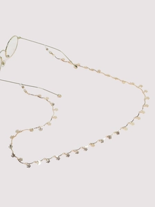 Detail of golden glasses chain with tiny flower motifs and wavy metal textures