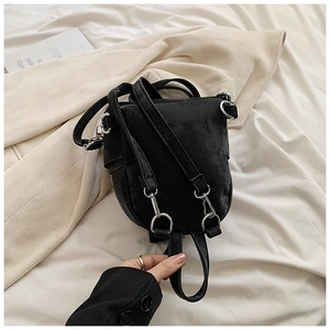 Détail d'un mini sac à dos en velours noir montrant les boucles métalliques argentées