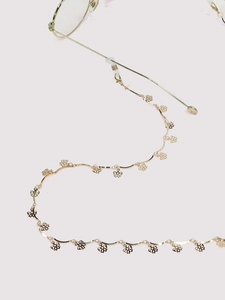 Close-up of golden metal eyeglass chain featuring delicate hollow flower charms detail