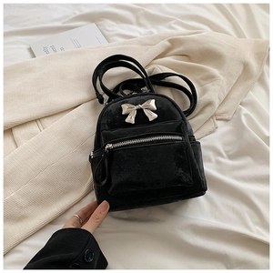Détail d'un mini sac à dos en velours noir avec un nœud argenté et une poche zippée