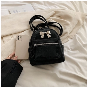 Détail d'un mini sac à dos en velours noir avec nœud en métal argenté et fermeture éclair
