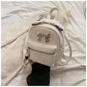 Détail d'un mini sac à dos en similicuir crème avec un nœud métallique argenté