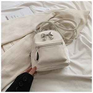Détail du mini sac à dos en cuir PU crème avec nœud en argent et poche frontale