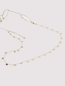 Detail of gold butterfly eyewear chain with delicate metal charms on round glasses