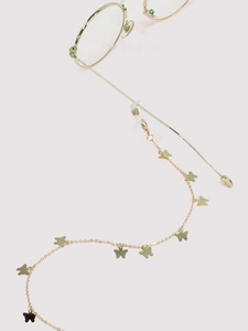 Close-up of golden eyewear chain with butterfly charms and silicone loops on pink background